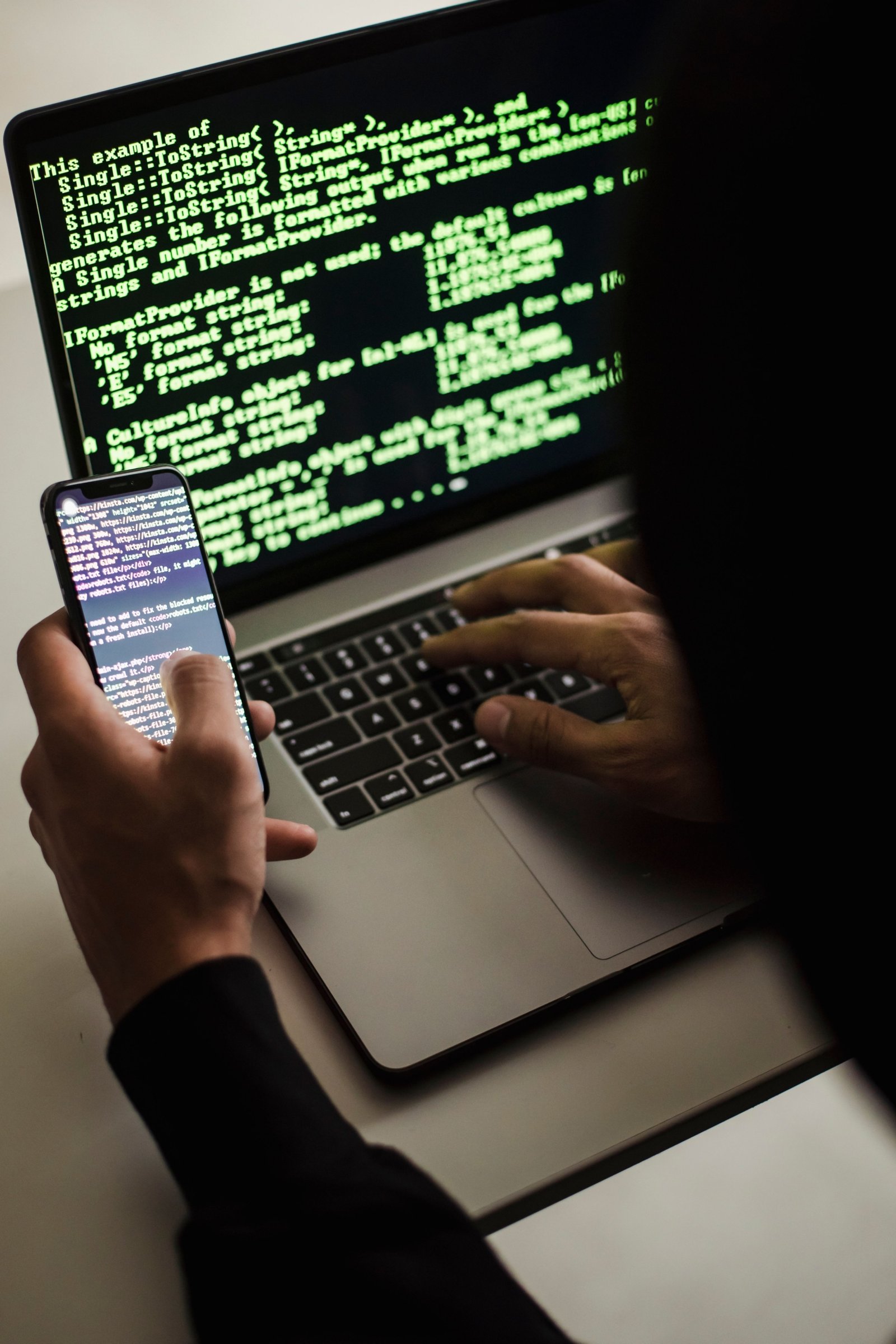 Security researcher reviewing exploit code on laptop and mobile during a manual penetration test